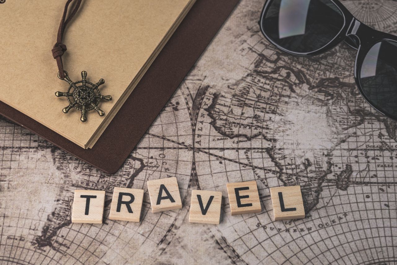 journey Close-up of travel items including map, helm pendant, notebook, and sunglasses.