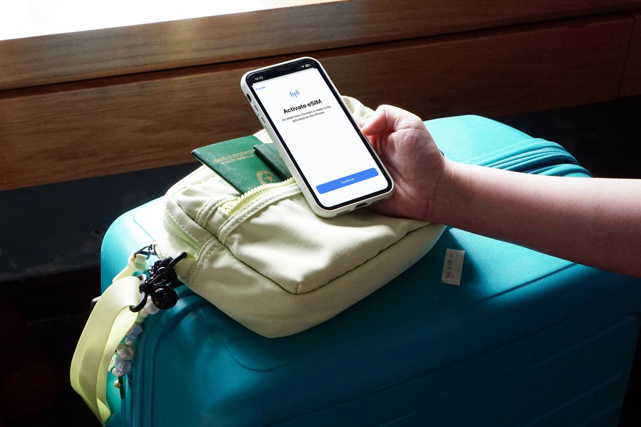 team-02 Close-up of a traveler activating eSIM on a smartphone over luggage, ready for a trip.