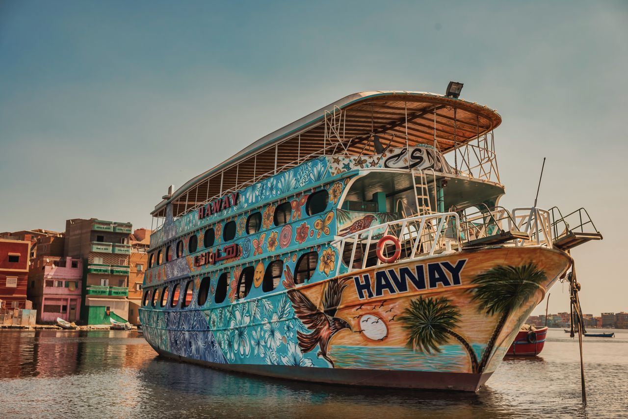 Crafting Captivating Headlines: Your awesome post title goes here Vibrant boat with artistic motifs docked in a serene urban setting during sunset.