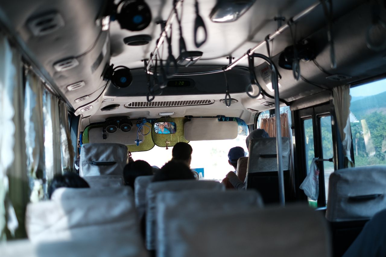 Home A typical day inside a Vietnamese bus with passengers traveling and scenic views outside.