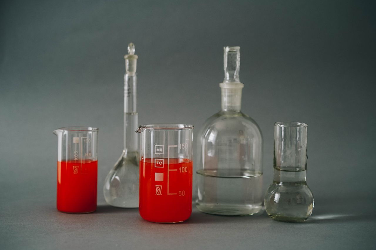 team-01 Close-up of laboratory glassware with colorful red liquids used in a chemistry lab.